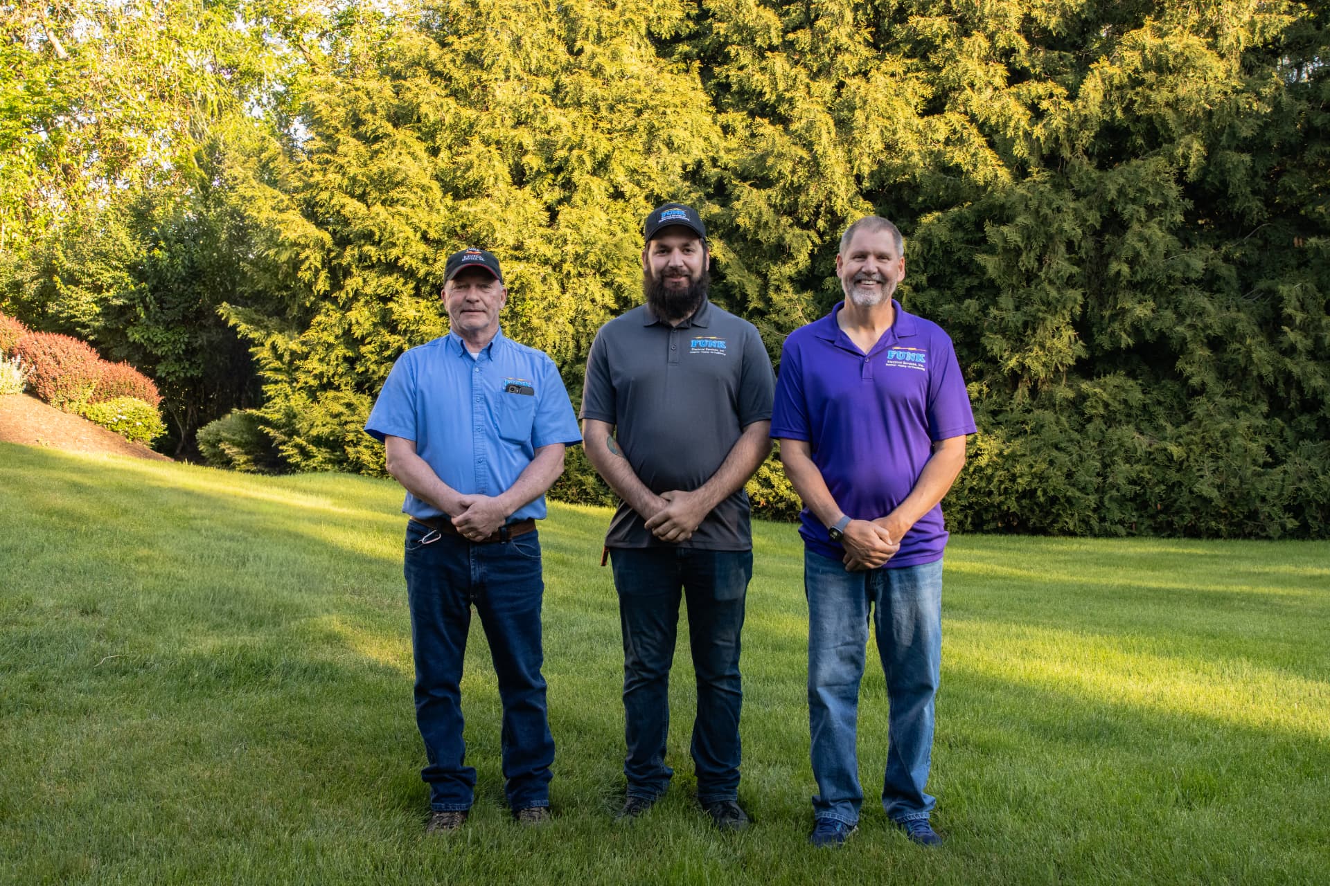 Three Funk Electrical service managers standing outdoors in company shirts